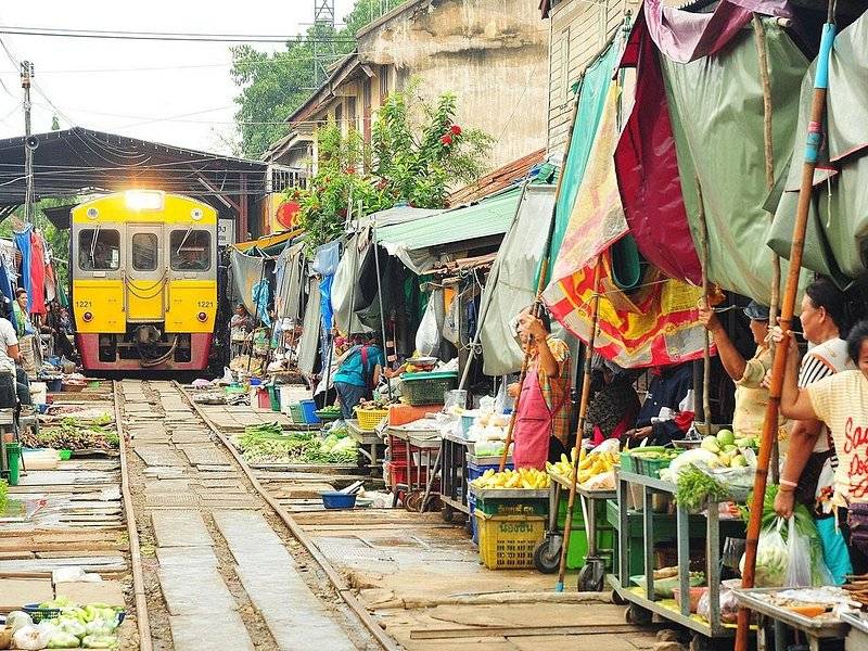Market stalls packed against the rails at Maeklong Railway Market