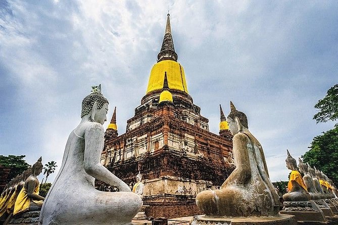 Rows of seated Buddhas in yellow sashes ringing the great chedi at Wat Yai Chai Mongkhon